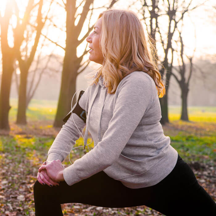 Mature woman exercising in the park, stretching