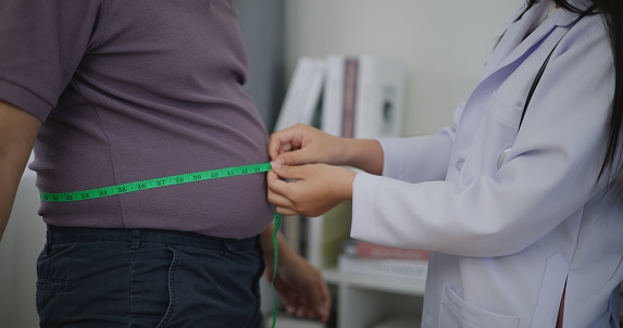 Female Nutritionist Measuring the Waist of an Overweight Man in a Weight Loss Clinic